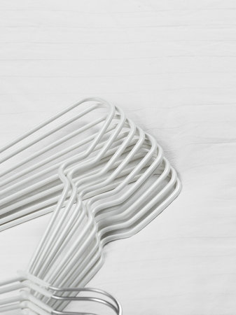 A generous bunch of white clothes hangers are neatly stacked on top of each other on a clean, white surface that brightens the sceneの写真素材