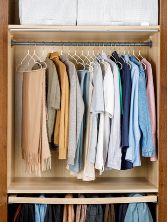 There exists a closet that is fully stocked with a variety of clothes, which notably includes cozy sweaters and stylish scarvesの写真素材