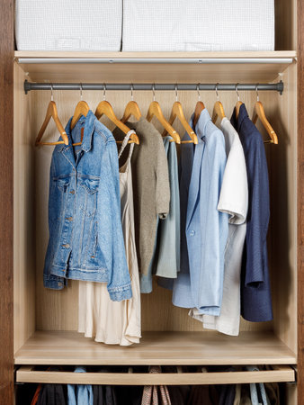 A closet that is filled with various clothes neatly hanging on sturdy wooden hangers, showcasing an array of garments and stylesの写真素材
