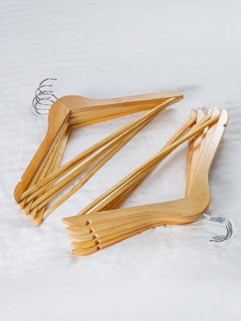 A collection of wooden hangers is neatly stacked on top of one another resting on a clean white surface, showcasing their natural texture and designの写真素材