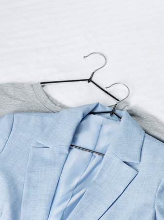 A light blue jacket is hanging gracefully on a hanger positioned next to a stylish gray jacket that complements it perfectlyの写真素材