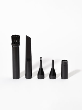 A collection of black vacuum cleaner attachments is displayed neatly on a clean white surface, showcasing their unique designs and functionalitiesの写真素材