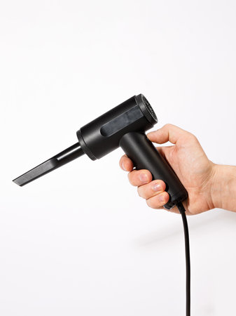 A person is confidently holding a stylish black hair dryer firmly in their hand, ready to use it for hairstyling or drying hairの写真素材