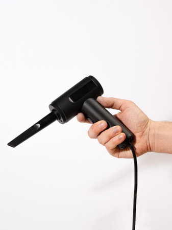 A person is currently holding a black vacuum cleaner firmly in their hand, demonstrating the use of this electronic cleaning deviceの写真素材