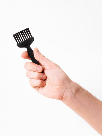 A human hand is firmly gripping a small black brush designed for various cleaning tasksの写真素材