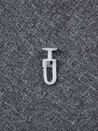 A white plastic hook is currently positioned on the surface of a gray carpet, creating a contrast...
