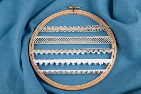 White sewing ribbons set on hoop over blue background