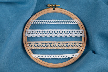 White sewing ribbons set on hoop over blue backgroundの写真素材