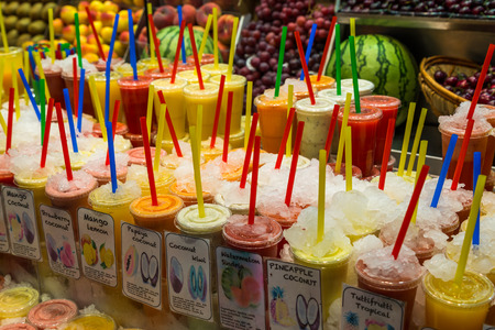 Variety of fruit juices in plastic glasses preserved in ice, ready for sale, in the market of La BoquerÃaのeditorial素材