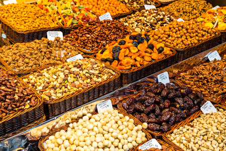 Variety of grains such as nuts, datils, raisins, pistachios, macadamia, ready for sale in the market of La Boqueriaのeditorial素材