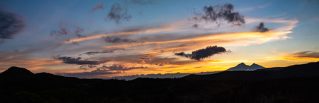 Panorama Sunset with orange clouds, blue sky, mountain silhouette, and Andean paramoの写真素材