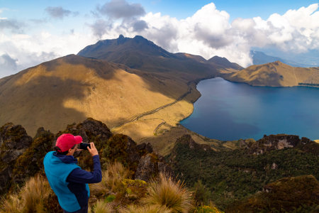 Mojanda, Tabacundo, Ecuador, January 9, 2022: An anonymous mountaineer takes photos of the beautiful landscape of the Mojanda lagoons and the Fuya Fuya hill on a sunny day in early 2022.のeditorial素材