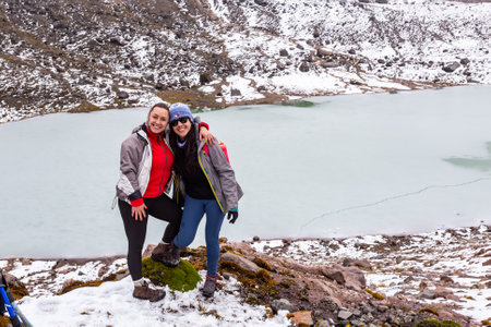 Ilinizas, Machachi, Ecuador, August 30, 2023: A couple of girls is surprised by the photographer while they hug at the edge of the Los Patos lagoonのeditorial素材
