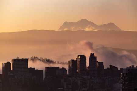 View of the Antisana volcano in the mist at dawn with some buildings of the city of Quito in the foreground.の写真素材
