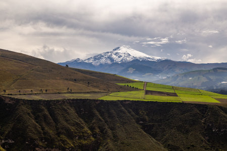 Cayambe volcano, the only one crossed by the equinoctial line, is shown in the morning, between the green of the fields and the whiteness of the clouds.の写真素材