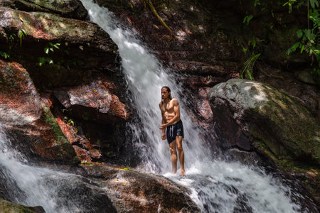 A man standing in the middle of the rocks of a small waterfallの写真素材