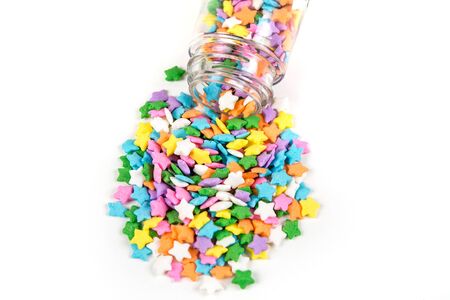 Assorted rainbow colored sprinkles and bottle isolated on white backgroundの写真素材