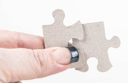 Manicured hands holding puzzle pieces isolated on white backgroundの写真素材