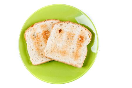 Two whole grain slices of bread toasted on a ceramic plate isolated on white backgroundの写真素材