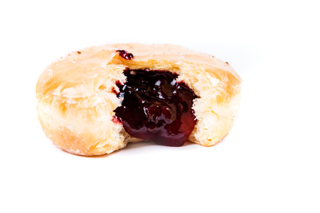 A frosted jelly filled donut with a bite out of it isolated on a white backgroundの写真素材
