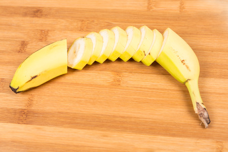 Banana cut up shallow depth of field isolated on wood backgroundの写真素材