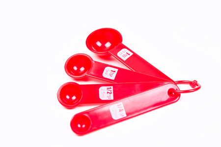 Red measuring spoons isolated on white backgroundの写真素材