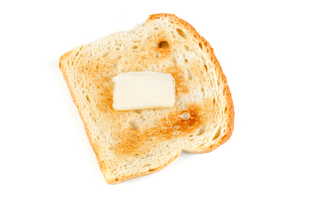 Toasted whole grain bread with a pat of butter isolated on white backgroundの写真素材