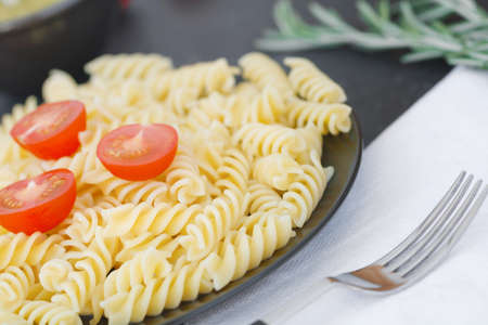 Italian pasta with tomatoes on the black plate