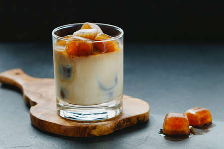 Iced coffee with milk on a wooden board on a black table.の写真素材