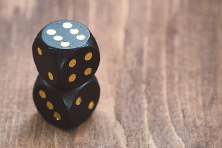 Close-up of black dice on a wooden tableの写真素材