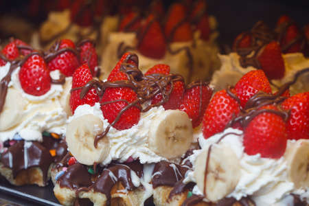 Belgian waffles with whipped cream, chocolate and strawberries on the display caseの写真素材