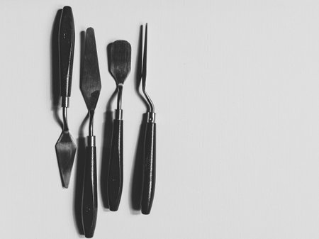 Black and white photography of palette knives over the blank canvas.