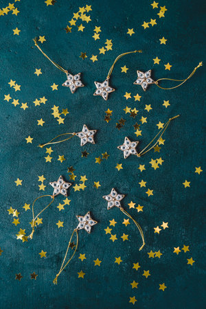 The New Year or Christmas festive flat lay with golden stars over a dark green background.