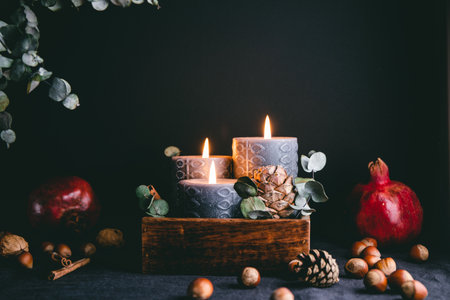 New Year festive decorations with wooden box and black burning candles in a dark interior.