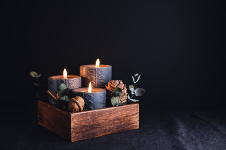 New Year festive decorations with wooden box and black burning candles in a dark interior.の写真素材