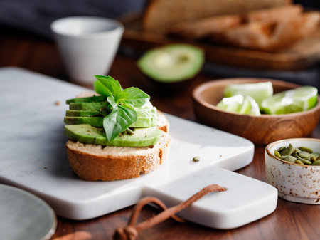 Avocado toast with pepitas and fresh basil on a white marble cutting board. Home cooking, healthy...
