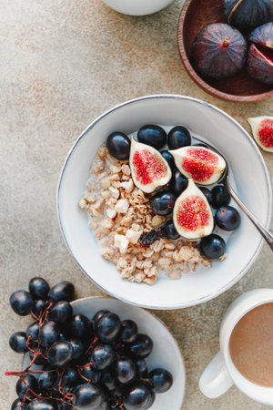 Top view of a breakfast bowl with granola, blue grape and fig slices. Healthy vegan eating flat layの写真素材