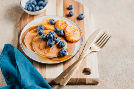 Close up of pancakes with grilled peaches, fresh blueberry and maple syrup.