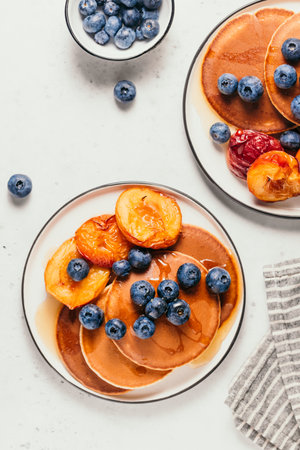 Top view of pancakes with grilled peaches, fresh blueberry and maple syrup.の写真素材