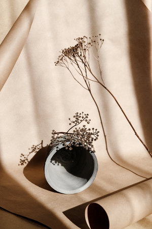 Abstract creative minimal composition with a clay pot and dry grass against kraft paper. Natural and ecological products concept.の写真素材