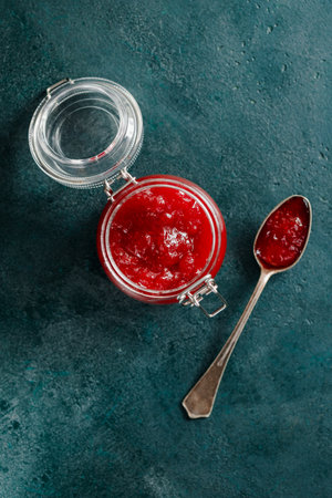 Top view of strawberry jam in a glass jar on a green background.の写真素材