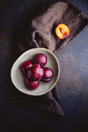 High angle view of fresh purple plum on a dark linen. food photography still life.の写真素材