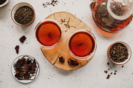 Different types of tea. Black, green and hibiscus sorts on a white table with teapot and glasses.の写真素材