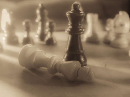 Chess pieces and kitchen knife. Strategy game. It is played on a 64 square black and white board.