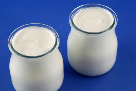 Tubs of natural yogurt, derived from cow's milk. Food product. Dairy product.