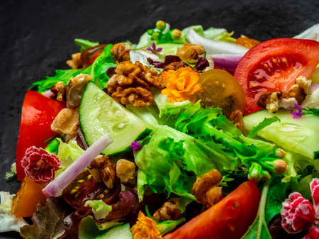 Salad of different types of lettuce, tomato, onion, cucumber and nuts.の写真素材
