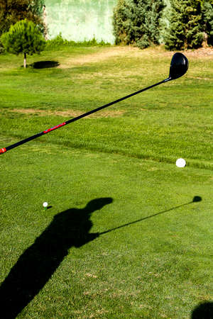 The shadow of the golf player is cast on the grass of one of the holesの写真素材