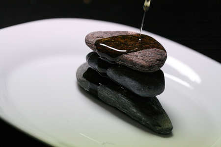 Extra virgin olive oil, falling on some river stones on a plate.