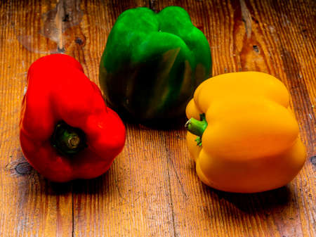 Still life of peppers in three colours on wood