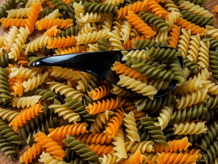 Black spoons with pasta on wooden tableの写真素材